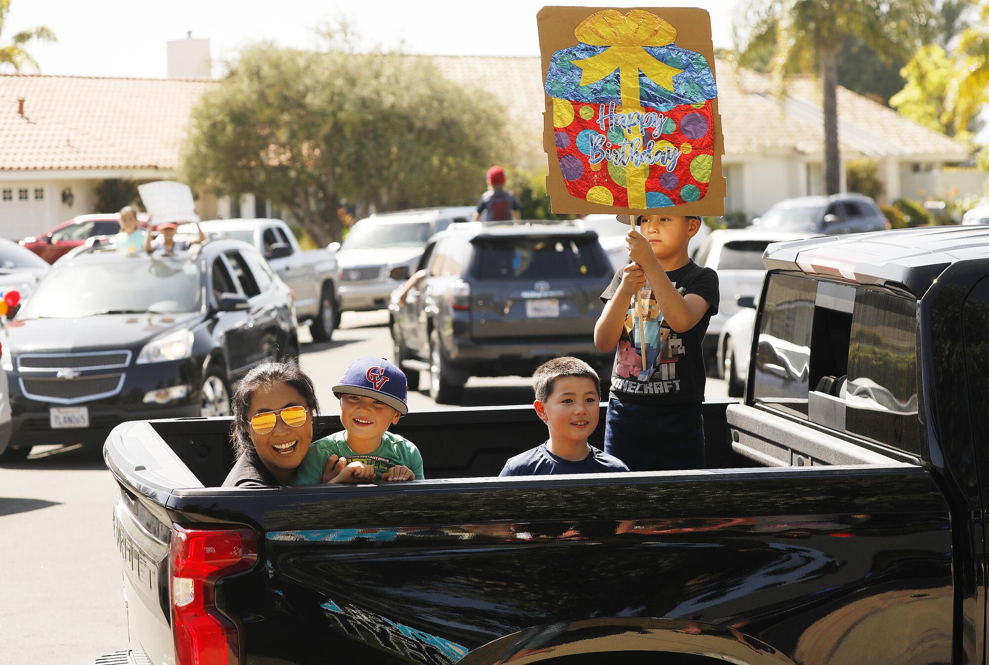 Catherine Boys and her three children Christopher, Nicolas and Jonathan cheer as they pass Peyton during his drive-by birthday party.