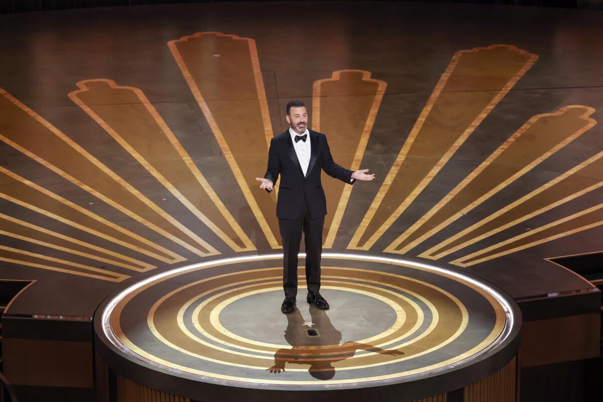 A man in a tuxedo stands within concentric circles onstage