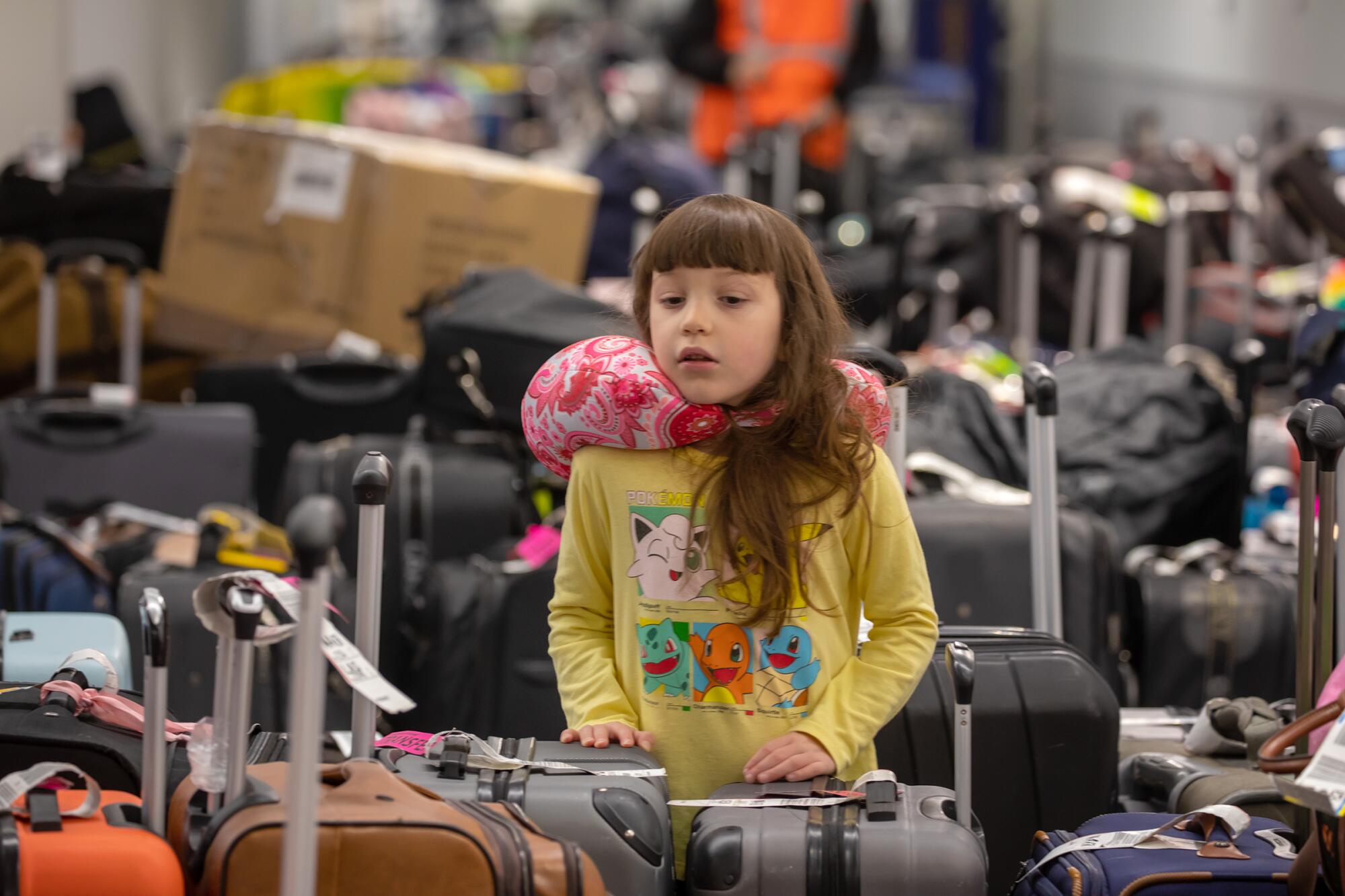 Ryker Salazar, 5, arriving from Dallas, searches for luggage among the sea of bags accumulated at baggage claim at LAX 