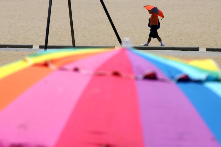 SANTA MONICA, CA - JUNE 29, 2024 - A beachgoer enjoys the shade of an umbrella while adding to the colors of summer along the pedestrian walkway in Santa Monica on June 29, 2024. (Genaro Molina/Los Angeles Times)