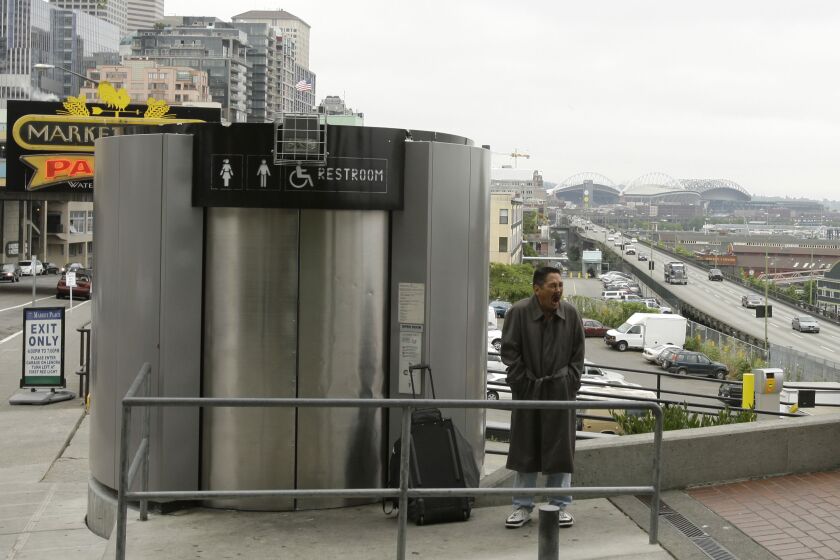 ** FILE ** This Thursday, July 17, 2008 shows a man as he waits for his turn to use an automated public toilet, near Seattle's famous Pike Place Market. City officials have finally gotten rid of five high-tech self-cleaning toilets that cost Seattle $5 million but sold online for just $12,549. (AP Photo/Ted S. Warren, file)