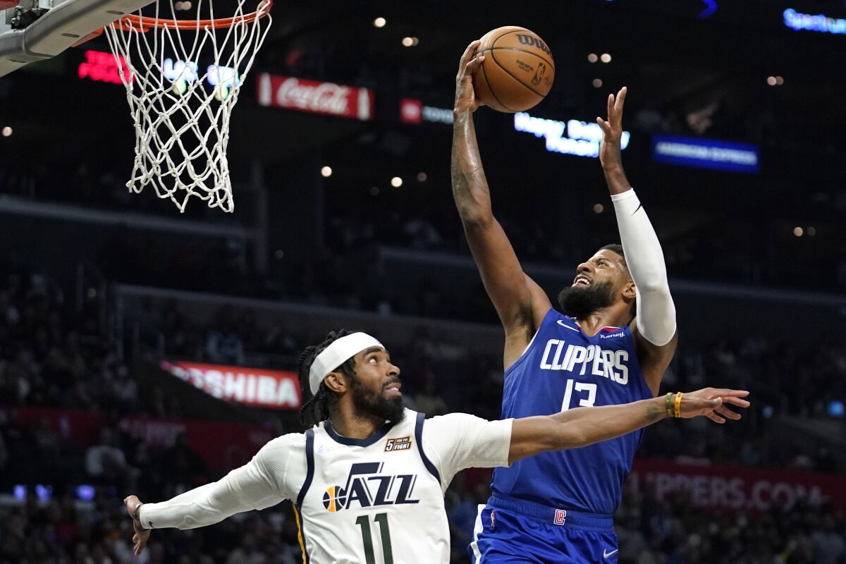 Los Angeles Clippers guard Paul George, right, shoots as Utah Jazz guard Mike Conley defends.