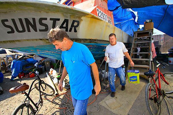 Brothers Doug, left, and Terry Herzik next to their fishing boat the Sunstar, which they're refurbishing in Oxnard. They share something inexpressible in the quiet work on a vessel they spent much of their adult lives on. See full story