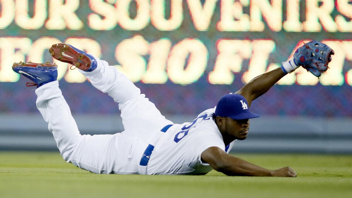 Dodgers right fielder Yasiel Puig holds up his glove to show he made a diving catch on a ball hit by Washington's Yunel Escobar in the fifth inning on Aug. 10.