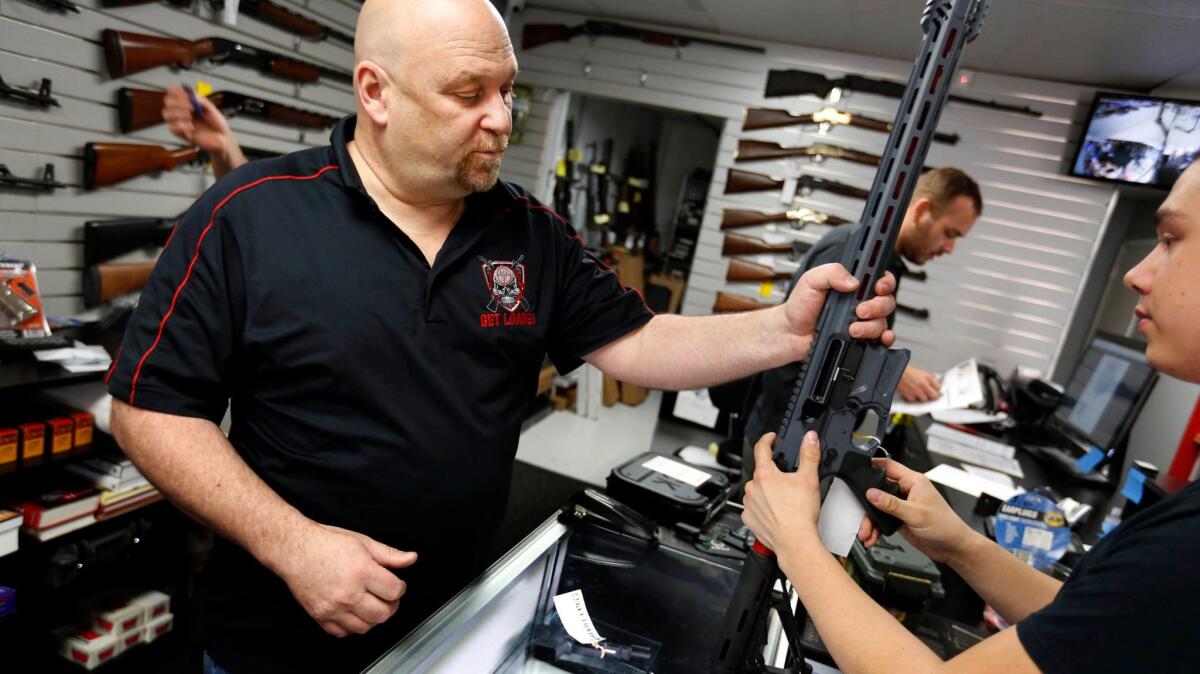 Terry McGuire, owner of Get Loaded in Grand Terrace, shows a customer a Cobalt Kinetics BAMF rifle about a week after the 2015 shooting rampage in nearby San Bernardino. New research confirms that gun sales in California tend to surge after a mass shooting.