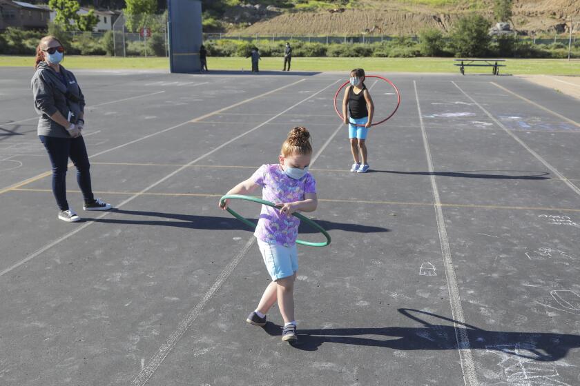 Under the supervision of Danielle Elliott (left), Lyric Gerber (middle) and Rayon Aguilera (right) play during break time at Chase Avenue Elementary School during the Cajon Valley Union School District's Emergency Child Care Program on May 5, 2020 in El Cajon, California. The district is offering free child care to essential workers.