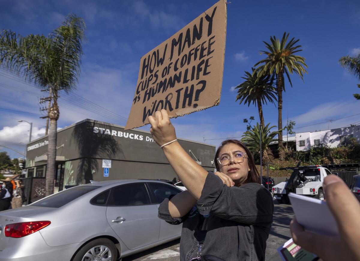 A woman holds a pro-union sign in front of a Starbucks store 