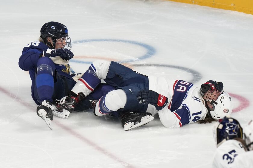United States' Brianna Decker (14) lies on the ice after colliding with Finland's Ronja Savolainen (88) during a preliminary round women's hockey game at the 2022 Winter Olympics, Thursday, Feb. 3, 2022, in Beijing. (AP Photo/Petr David Josek)