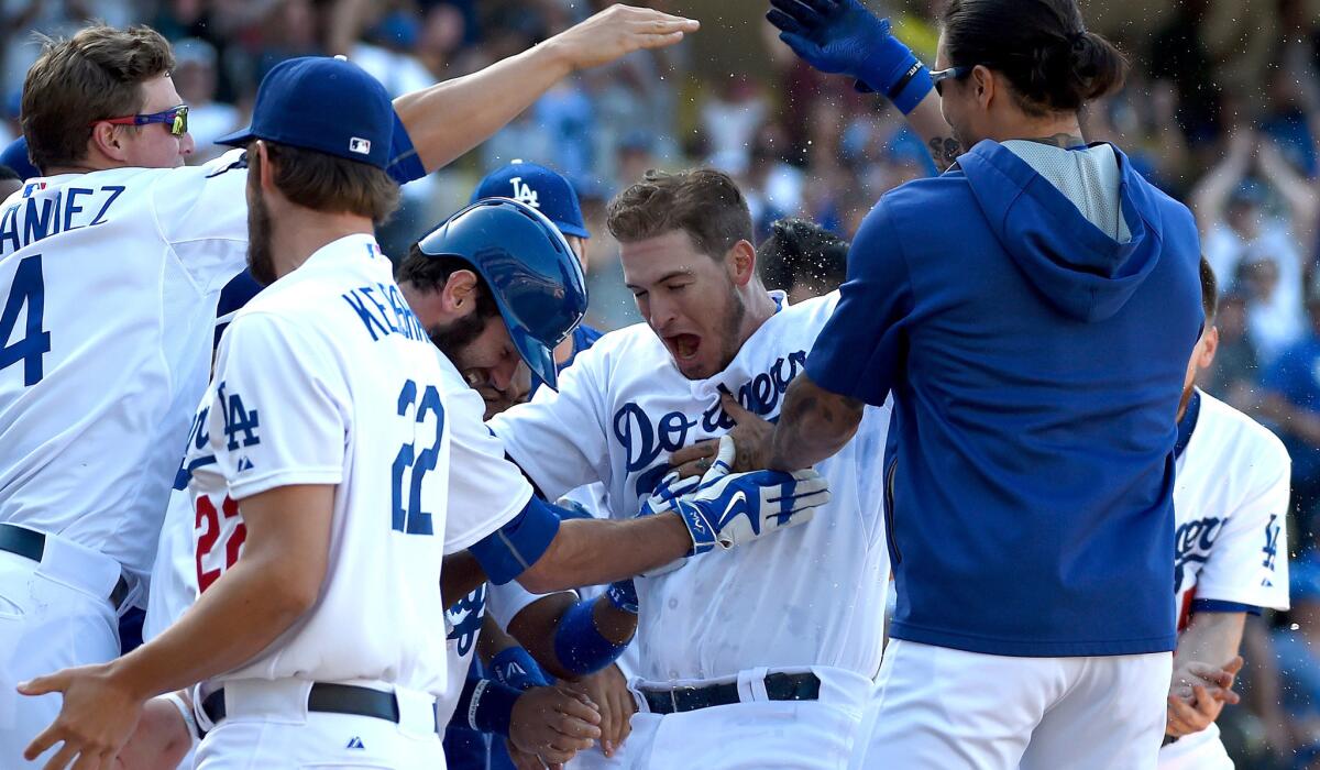 Dodgers catcher Yasmani Grandal, center, is swarmed by teammates after hitting a walk-off home run against the Diamondbacks in the 13th inning on Sunday afternoon at Dodger Stadium.