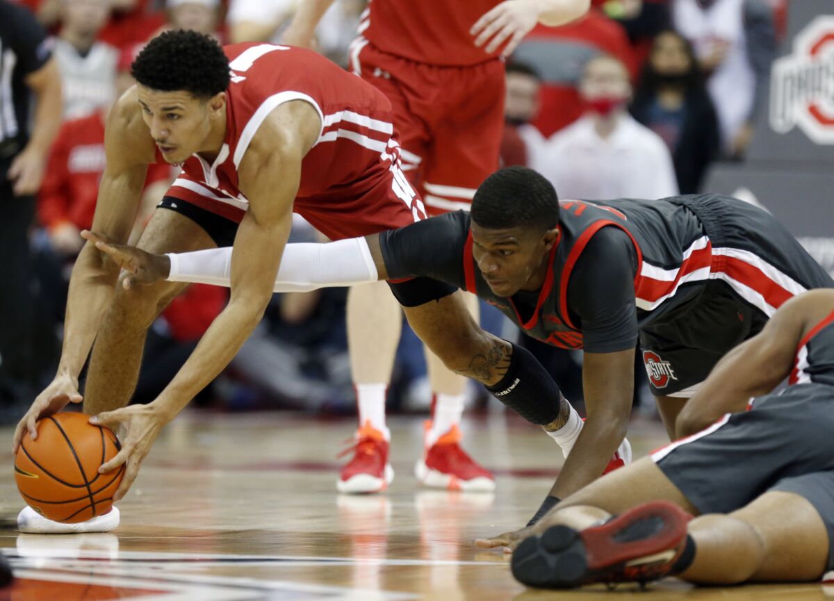 Wisconsin guard Jonathan Davis, left, and Ohio State forward E.J. Liddell reach for a loose ball during the first half of an NCAA college basketball game in Columbus, Ohio, Saturday, Dec. 11, 2021. (AP Photo/Paul Vernon)