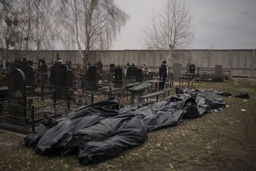 Bodies in black bags lie near tombstones 