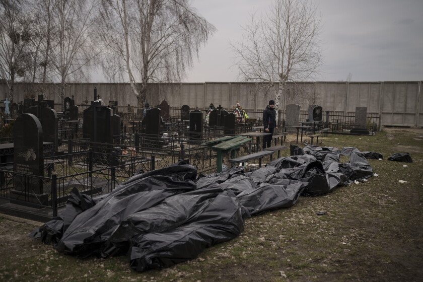 Bodies in black bags lie near gravestones