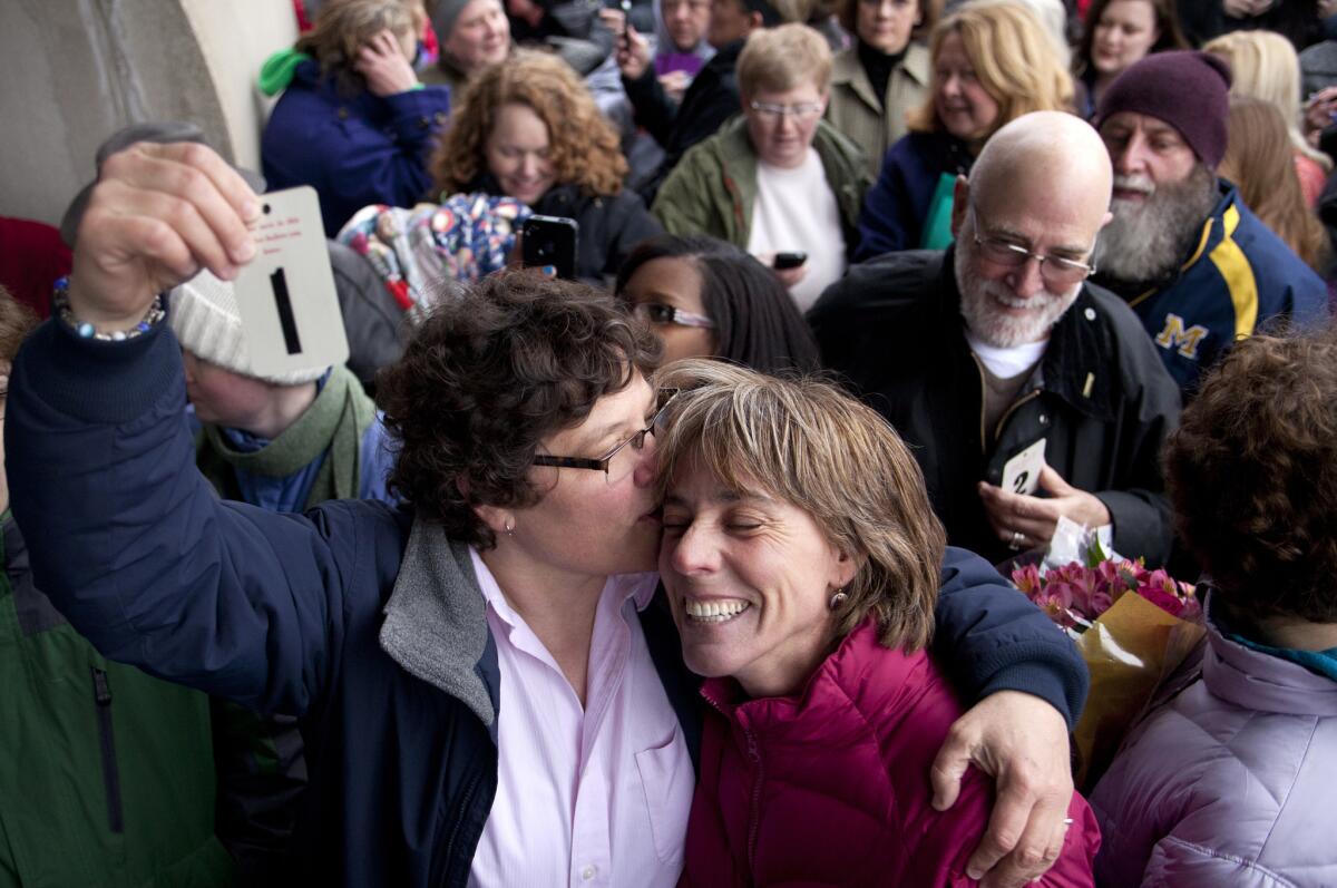 Elizabeth Patten, left, holds up the first marriage ticket to marry her partner Johnnie Terry in front of the Washtenaw County clerk's office in Ann Arbor, Mich., in March.