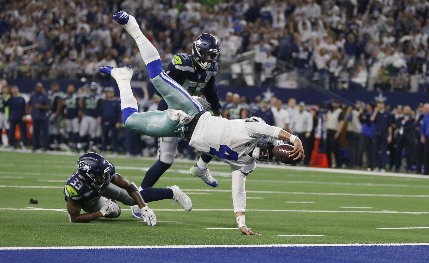 Dallas Cowboys quarterback Dak Prescott (4) flies for the goal line and makes a first down against Seattle Seahawks defensive end Frank Clark (55) during the second half of the NFC wild-card NFL football game in Arlington, Texas, Saturday, Jan. 5, 2019. (AP Photo/Ron Jenkins)