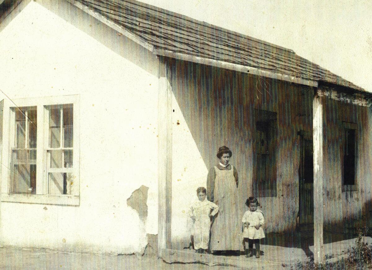 Image of a one-story house with a woman and two children standing out front.