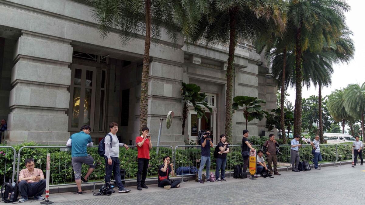 Journalists wait next to the Fullerton Hotel in Singapore for a glimpse of Kim Chang Son, North Korean leader Kim Jong Un's chief aide. With official information about the summit preparations scarce, reporters have resorted to paparazzi-style stakeouts.