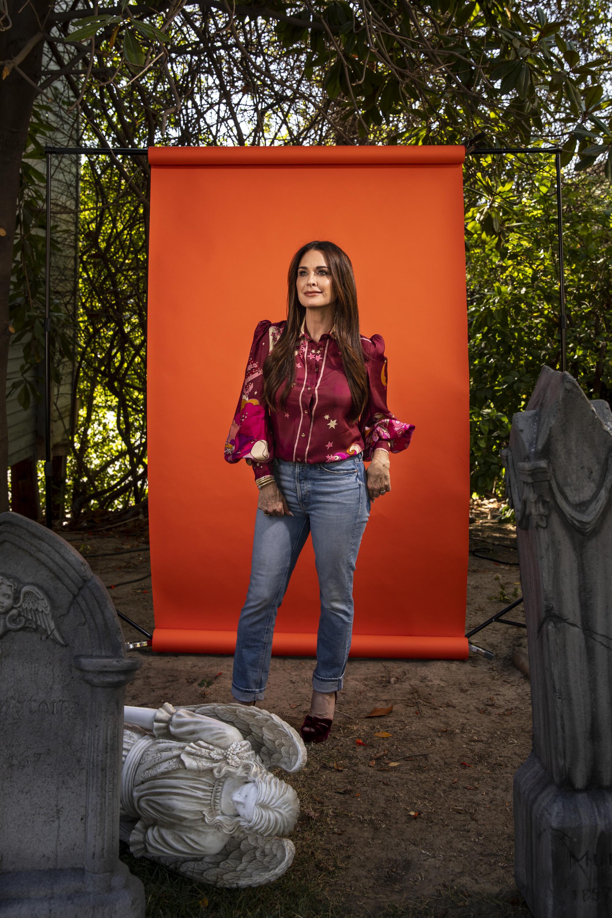 A woman stands in front of a graveyard set