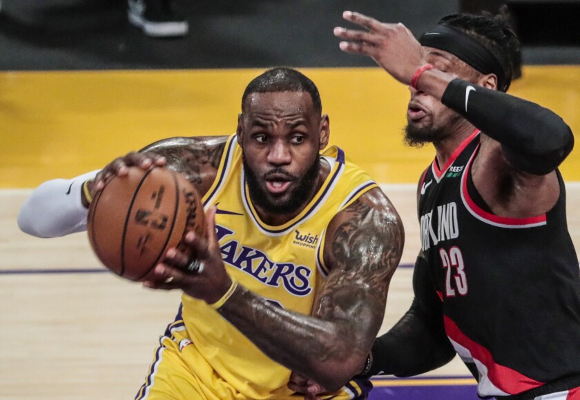 Lakers star LeBron James looks to pass while covered by Portland Trail Blazers forward Robert Covington.