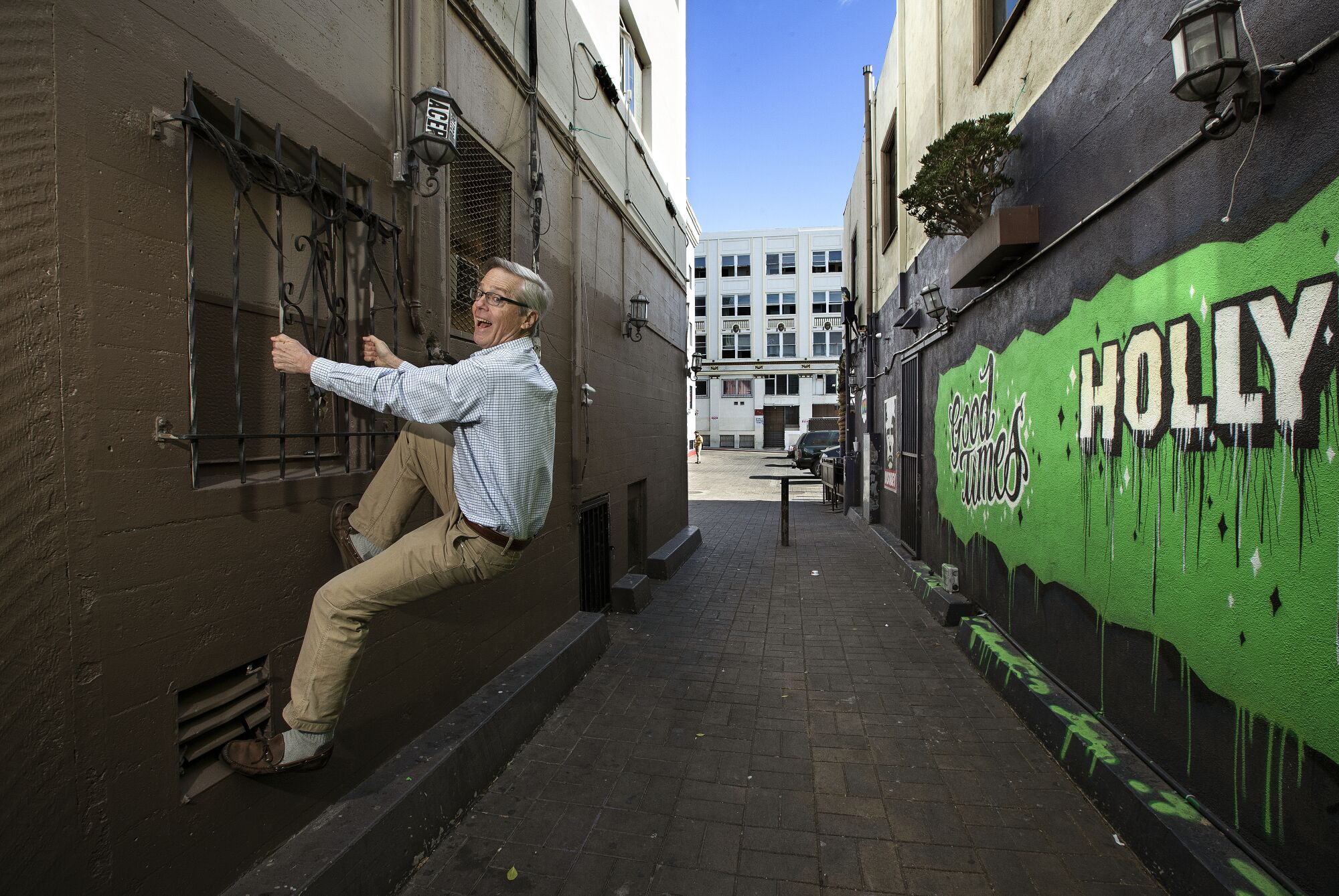 John Bengtson grips iron window bars in an alleyway