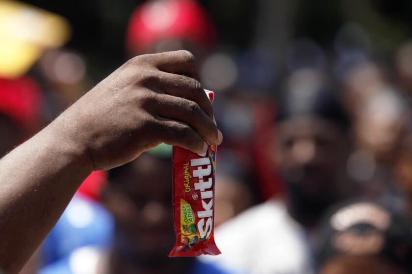 A man holds up a bag of Skittles candy after arriving with a motorcade of more than 200 bikers for a demonstration at the Georgia State Capitol, Sunday, July 28, 2013, in Atlanta. The crowd gathered in protest of gun violence and to urge the U.S. Department of Justice to press federal civil rights charges against George Zimmerman, who was found not guilty in the shooting death of unarmed teenager Trayvon Martin. (AP Photo/Jaime Henry-White)