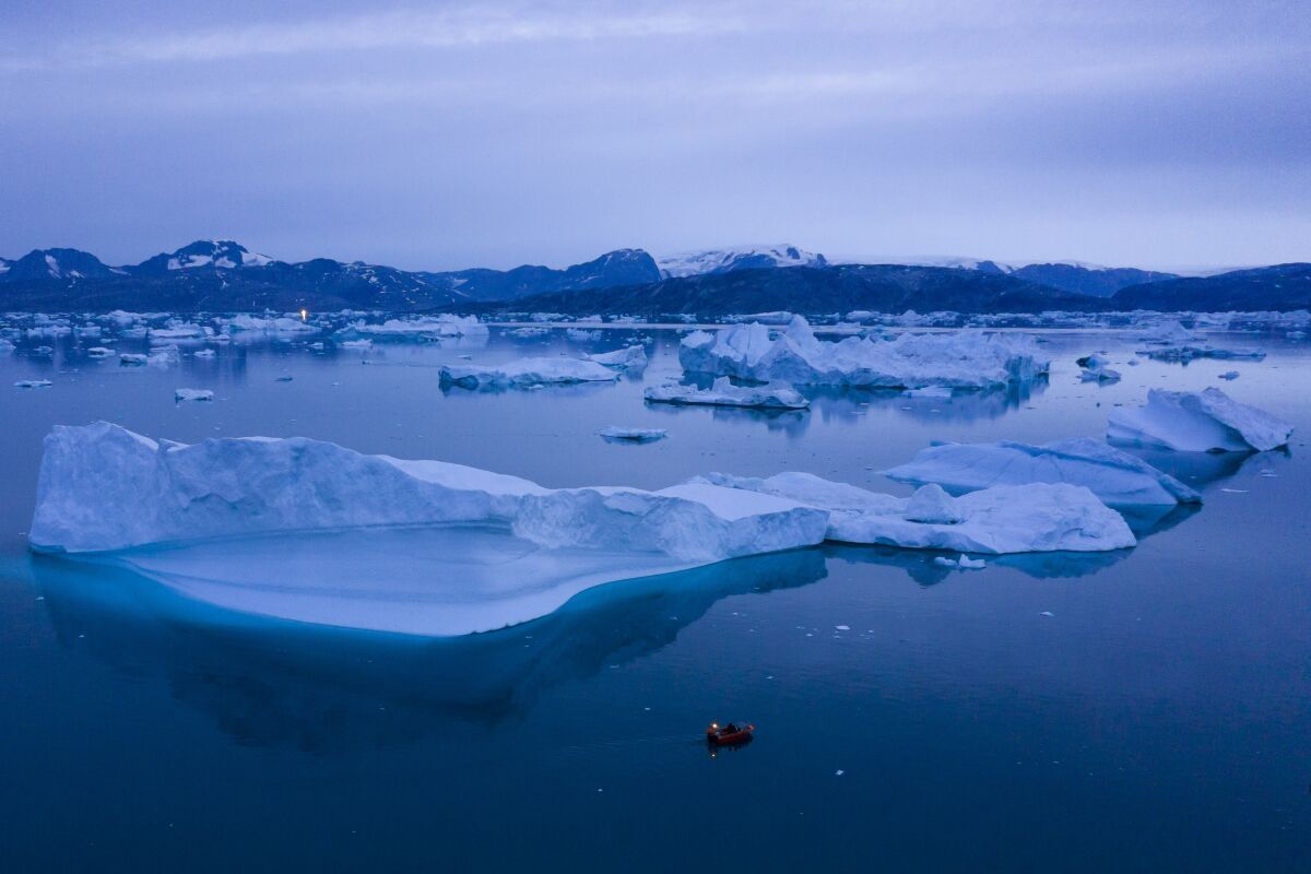 A boat navigates next to large icebergs near the town of Kulusuk in eastern Greenland.