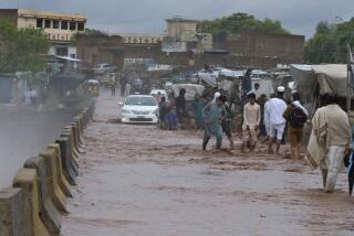 Gente vadeando un puente inundado junto a un arroyo desbordado por las lluvias, a las afueras de Peshawar, Pakistán, el lunes 15 de abril de 2024. (AP Foto/Muhammad Sajjad)