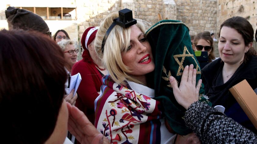 A member of the liberal Jewish religious group Women of the Wall wears phylacteries and a traditional prayer shawl as she holds a Torah scroll at the Western Wall in Jerusalem's Old City in March 2016.
