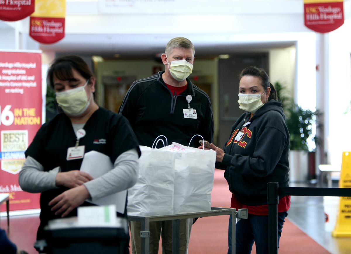 Chief Operating Officer Kenny Pawlek, center, and executive assistant Elen Borja, right, stand next to a Chinese food delivery from New Moon, at Verdugo Hills Hospital in Glendale on Tuesday, April 7, 2020.