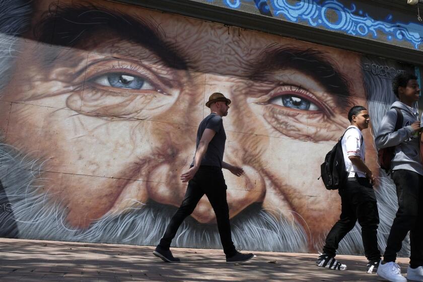 In this photo taken Wednesday, Aug. 29, 2018, people walk past a new mural of Robin Williams on Market Street in San Francisco. An artist is paying tribute to the late Robin Williams with a giant mural in San Francisco that depicts his blue eyes and nose framed by silver hair. The San Francisco Examiner reports Argentine muralist Andres Iglesias, who signs his art with the pseudonym Cobre, completed his wall-sized tribute to Williams on Sunday in the city's Tenderloin neighborhood. The artist says he picked Williams because he inspired him as a kid.(AP Photo/Eric Risberg)