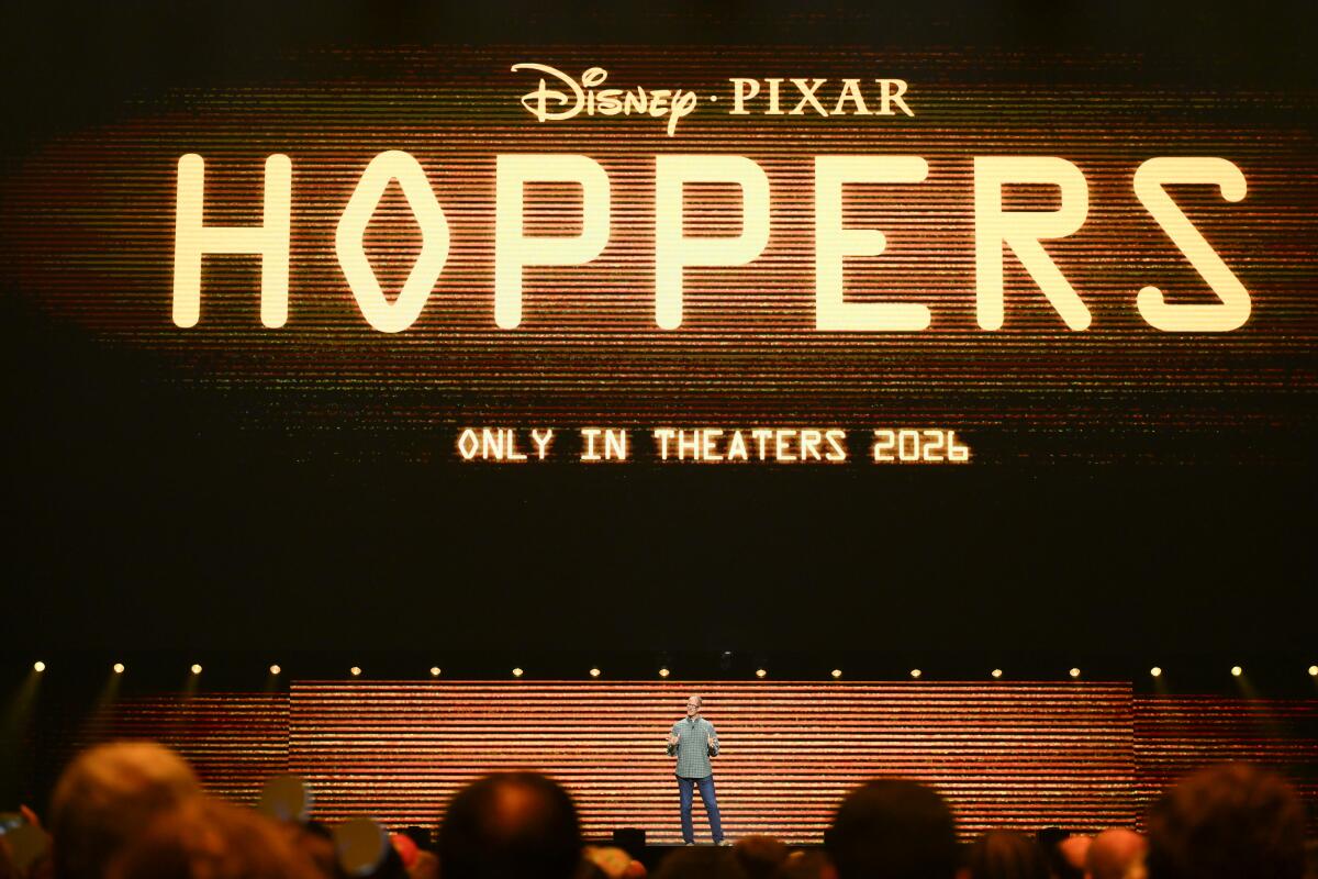 A man on stage standing beneath a logo for "Hoppers"