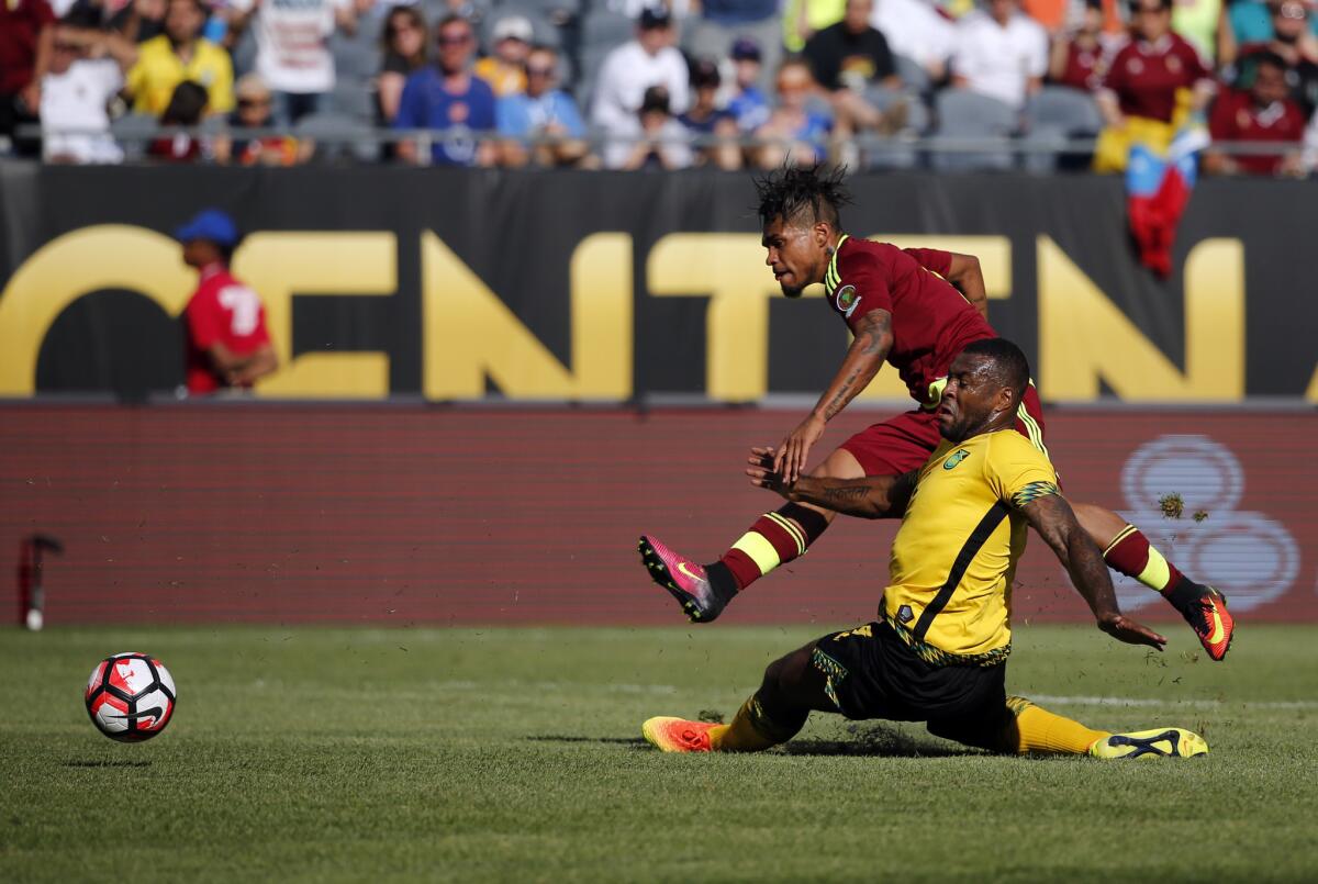 Venezuela's Josef Martinez, top, takes a shot on goal under pressure from Jamaica's Wes Morgan Sunday.