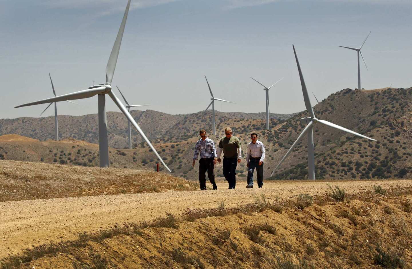 Mark Sedlacek, left, Chuck Holloway and Ken Silver of the Los Angeles Department of Water and Power walk among the wind turbines at the Pine Tree wind farm in the Tehachapi Mountains. Wind energy farms are being approved across ridgelines used by endangered condors and federally protected eagles. Recently, renewable energy companies and federal biologists have been trying to develop technologies to prevent those birds and others from colliding with the turbine blades.