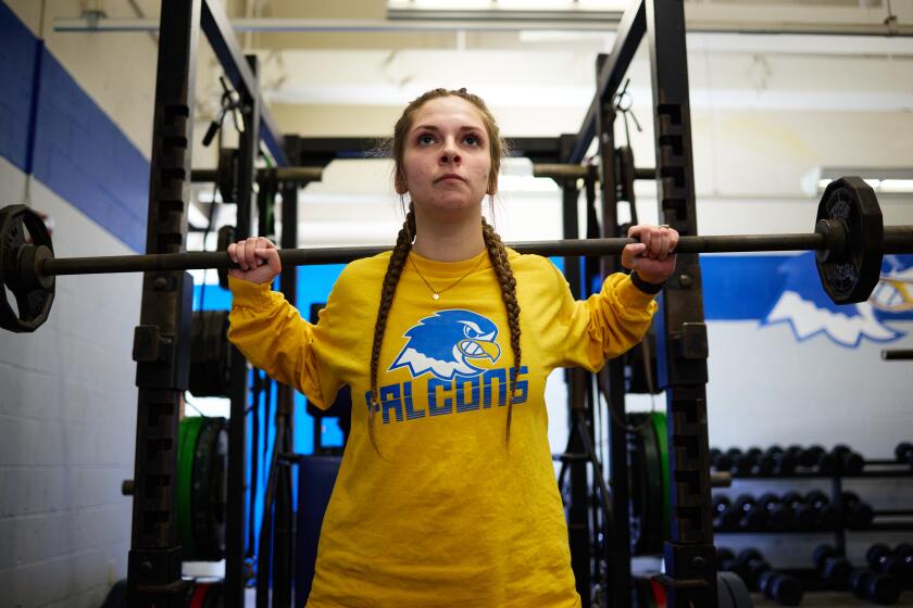 A college women's lacrosse team member lifts weights.