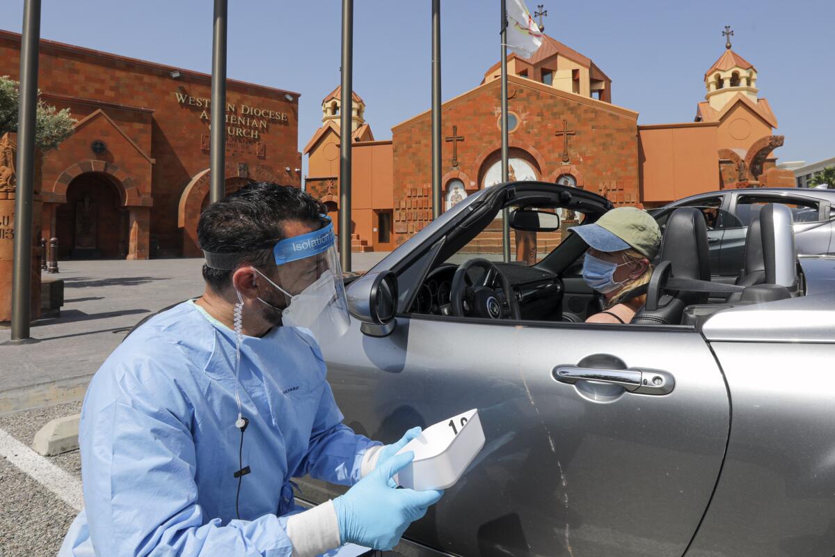 Edward Zaghikian gives Simone McFarland the result of her antibody test at a drive-through testing center May 9 in Burbank.