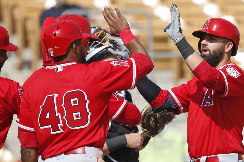 Los Angeles Angels' Kaleb Cowart, right, gets high-fives from teammates Joe Adell, left, Jarrett Parker (obscured) and Cesar Puello (48) in the fourth inning of a spring training baseball game Monday, March 4, 2019, in Glendale, Ariz. (AP Photo/Sue Ogrocki)