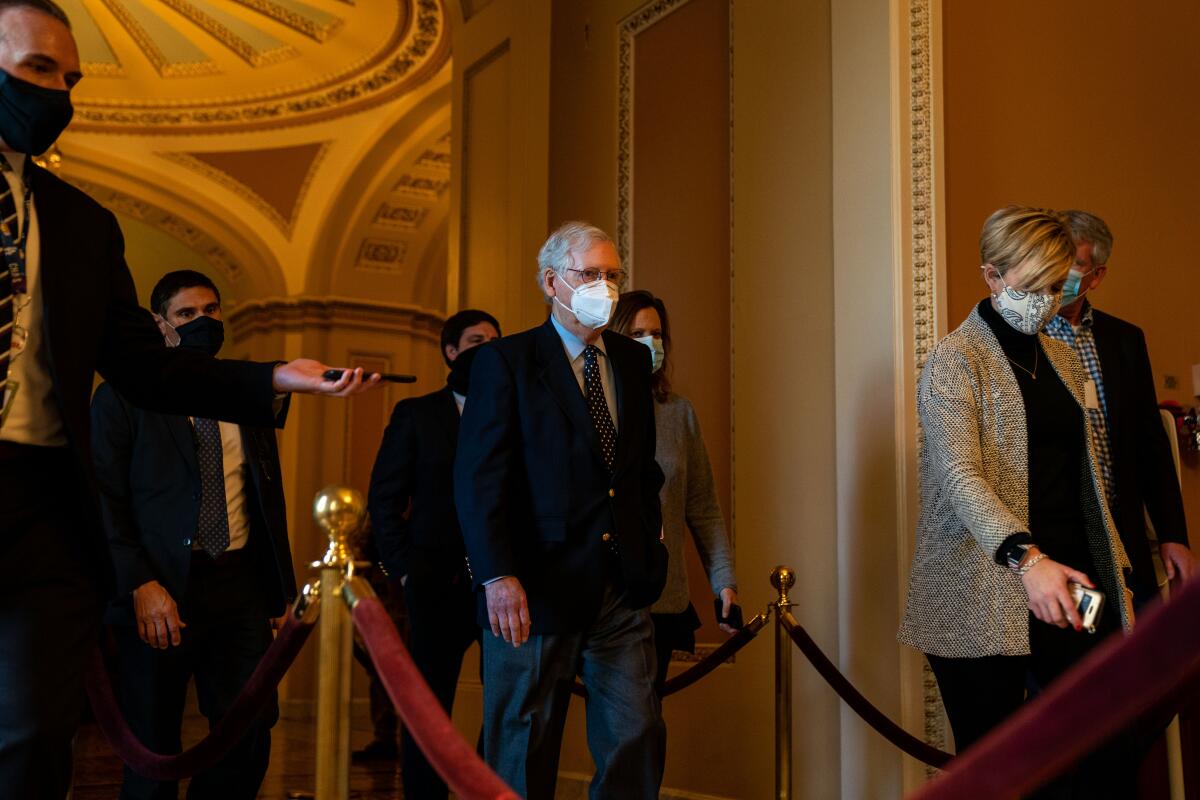 Mitch McConnell walks with others wearing masks inside the Capitol.