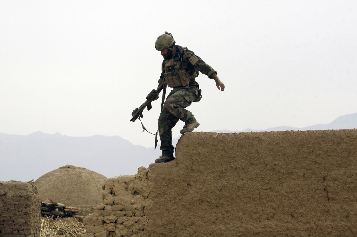 A member of U.S. special operations forces climbs down from a compound wall during a patrol in Afghanistan's Farah province in 2009.
