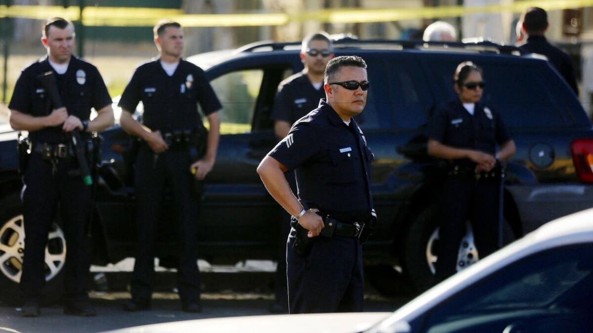 Los Angeles police officers monitor the scene of a shooting in the Nickerson Gardens housing project in Watts last summer.