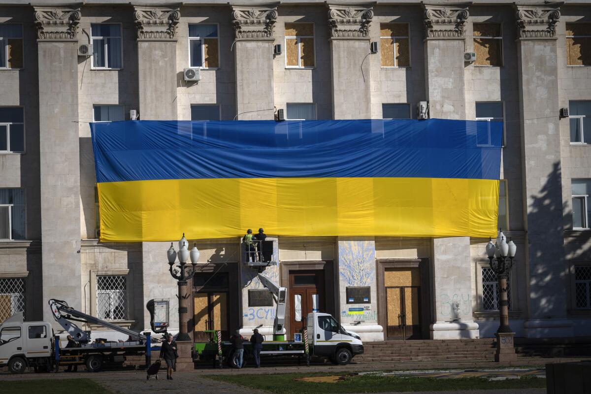 Ukraine municipal workers wearing protective vests and helmets decorate the wall of the regional administration building