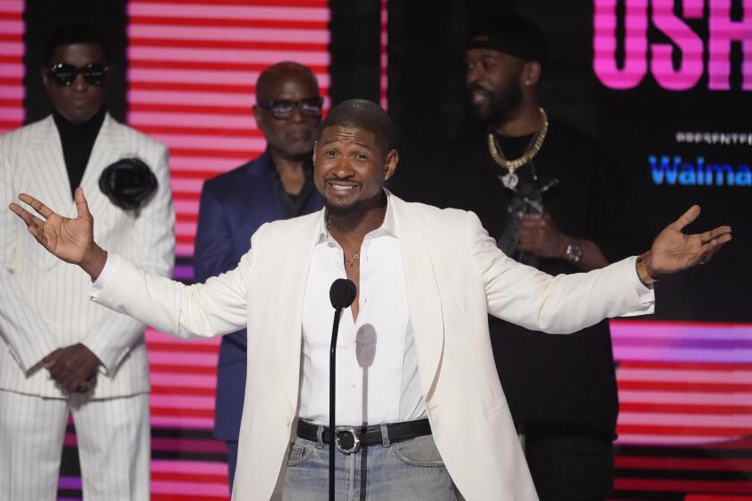 Usher acepta el reconocimiento a la trayectoria en los premios BET el domingo 30 de junio de 2024 en el Peacock Theatre de Los Ángeles. Babyface, atrás a la izquierda, y L.A. Reid, atrás al centro, miran. (Foto AP/Chris Pizzello)