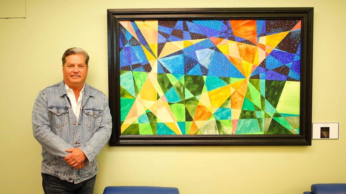 Chip Fesko stands next to one of his abstract geometric paintings, based on math lines, on display at the Newport Beach Central Library.