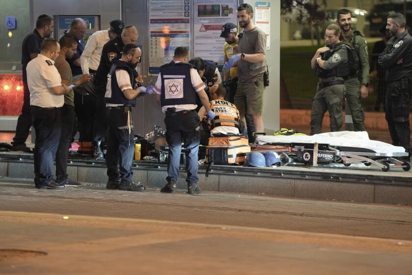 Israeli paramedics treat a suspected Palestinian attacker at the scene of a stabbing that wounded one person at a light rail stop in Jerusalem, Thursday, Sept. 21, 2023. Police said the man was shot and seriously wounded after carrying out the stabbing. (AP Photo/Mahmoud Illean)