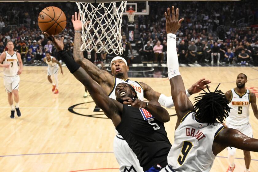 Clippers forward Montrezl Harrell powers his way for a layup against Nuggets forwards Torrey Craig and Jerami Grant during the first half of a game Feb. 28, 2020, at Staples Center.