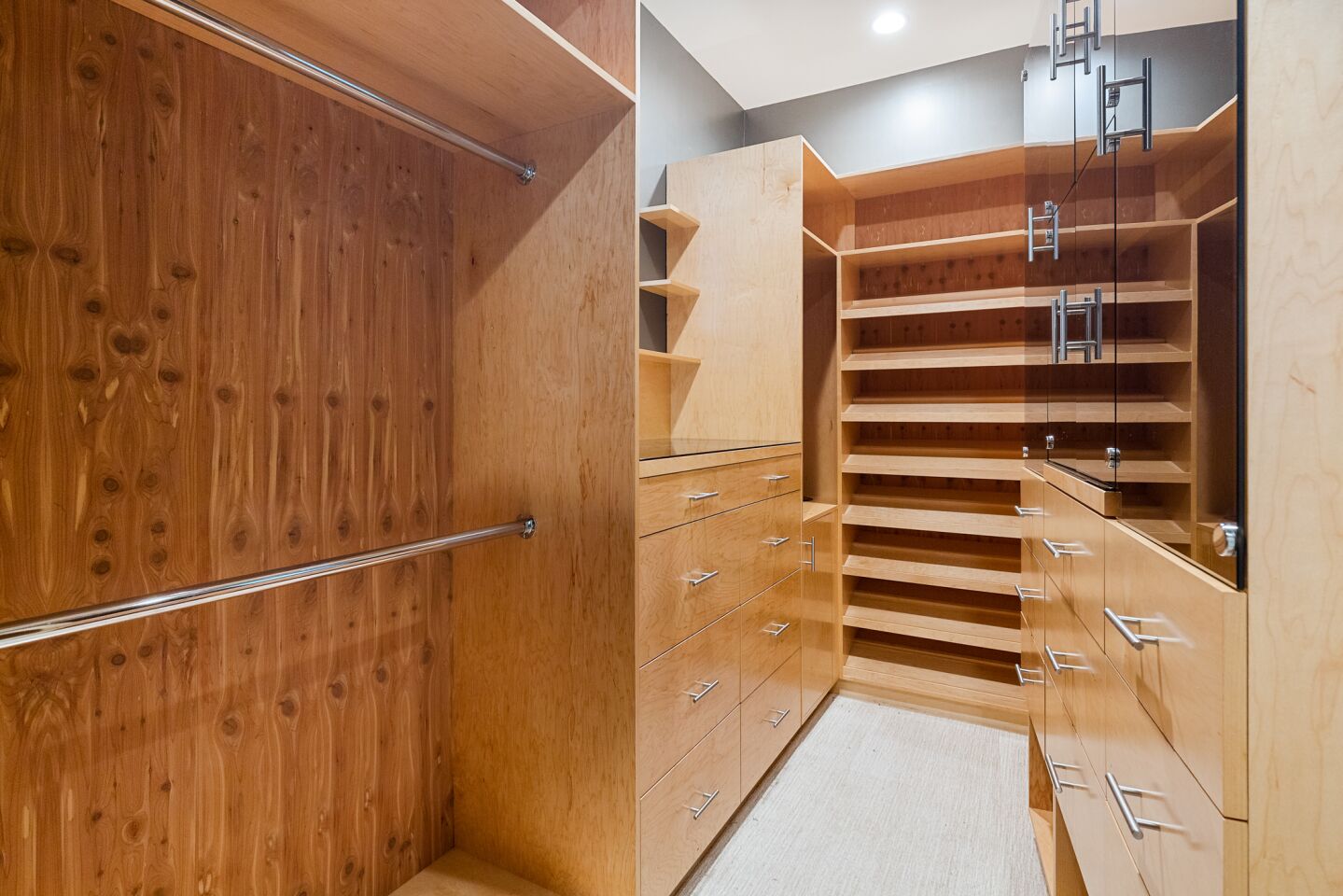 A walk-in closet with extensive wood cabinets and shelves.