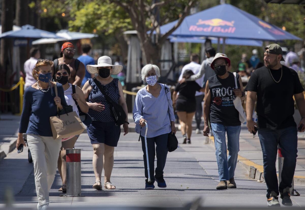 People, some wearing masks and some not, walk outside