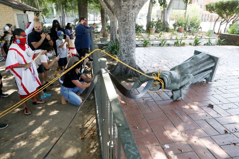 Activists topple the statue of Father Junipero Serra (1713 - 1784) at Father Serra Park in Pueblo Amigo on Saturday.