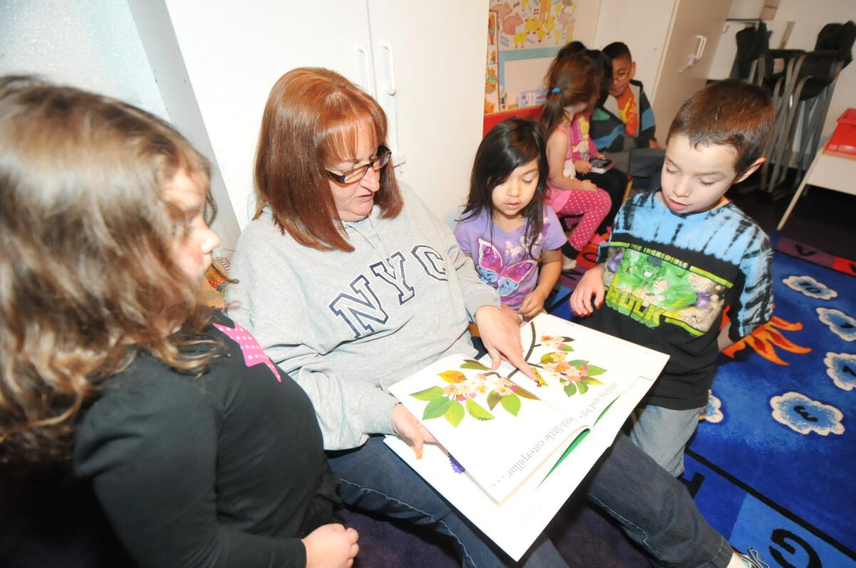Denise Sidney, of Sidney Family Day Care in Hesperia, reads to Ariana Sanchez, 5, left, Mya Mesa, 5, center right, and Nicklaus Gomez, 7.