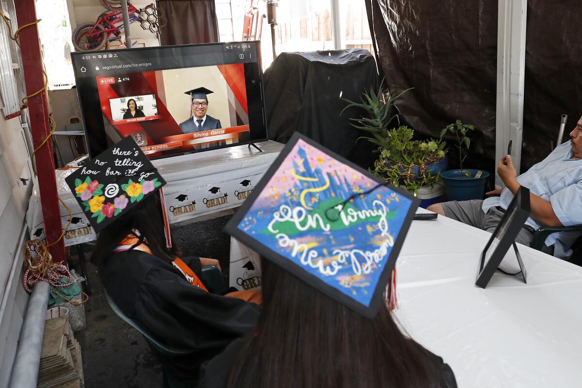 Los Amigos graduates Alexandra Lopez, left, and Karen Arzola, center, watch their virtual graduation ceremony on Friday.
