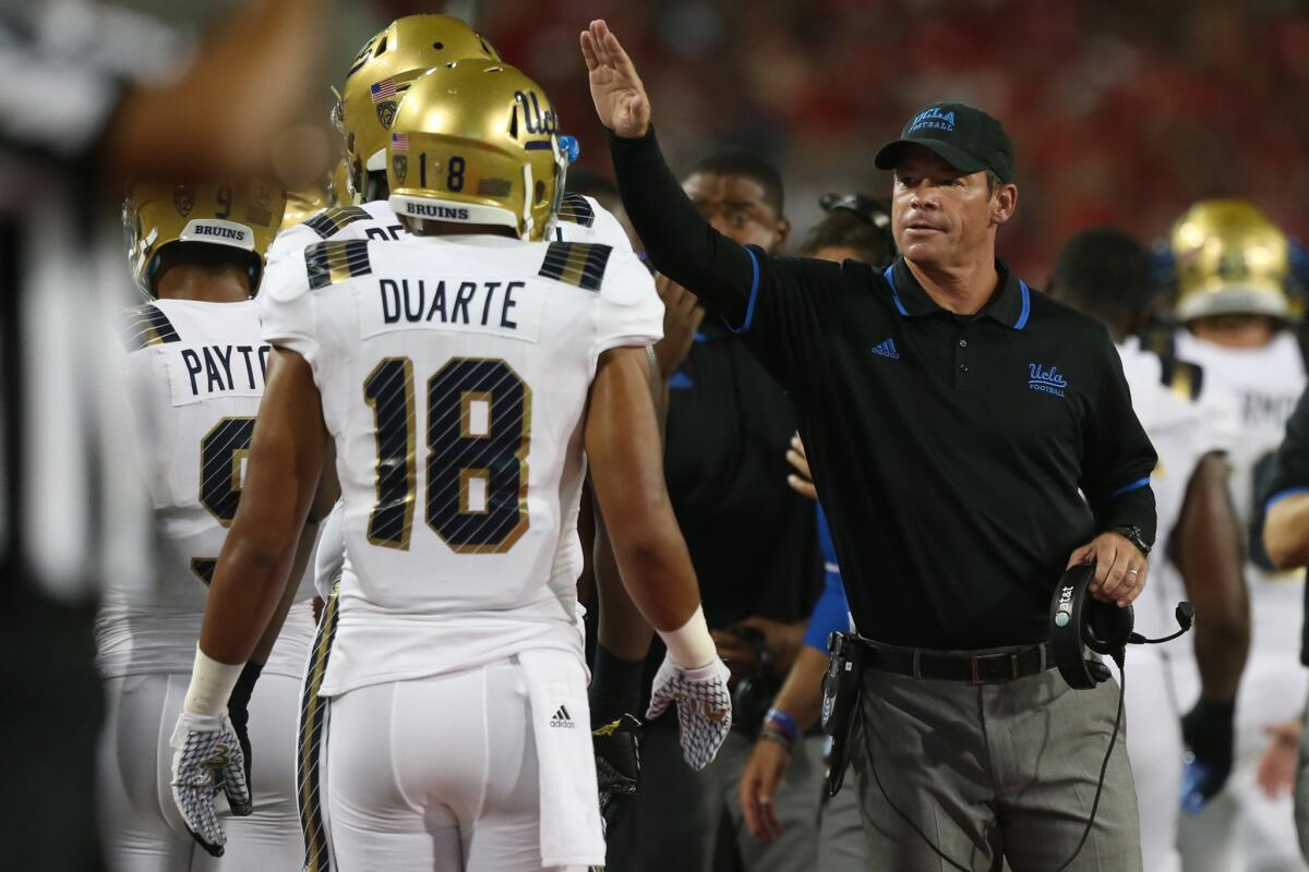 UCLA Coach Jim Mora reaches out to receiver Thomas Duarte after a scoring drive against Arizona during a game on Sept. 26.