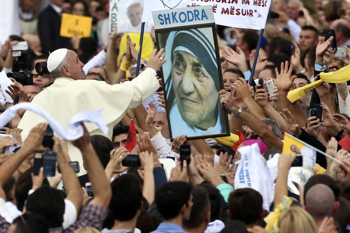 Pope Francis reaches for a poster of Mother Teresa as he is driven through the crowd in Tirana, Albania.